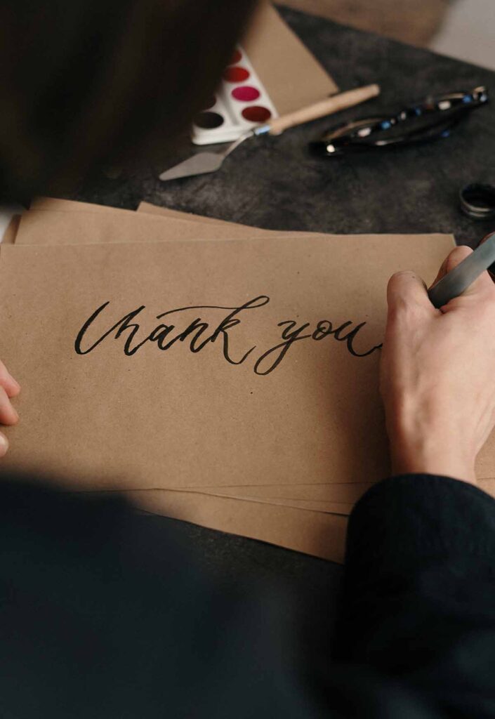 Person writing Thank You on paper with marker